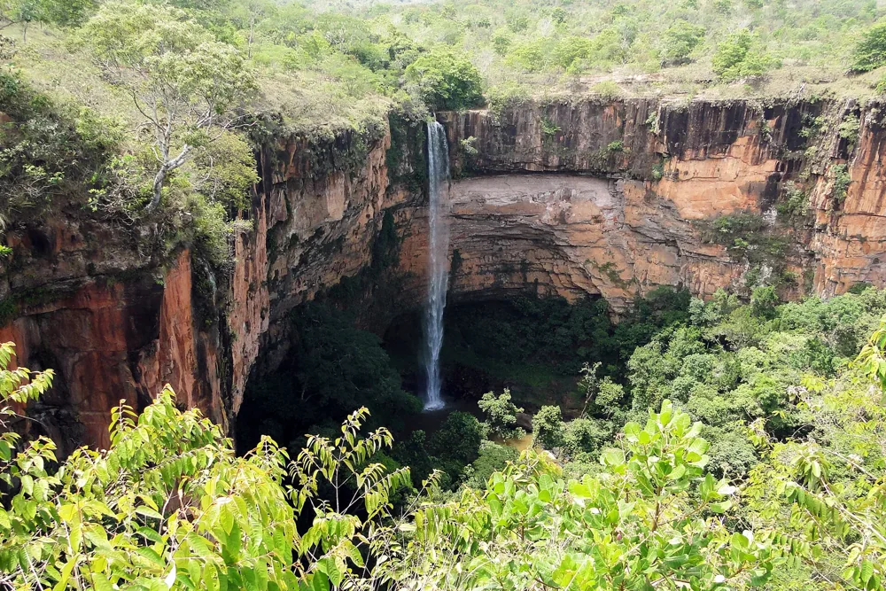Véu de Noiva waterfall descending between red sandstone cliffs